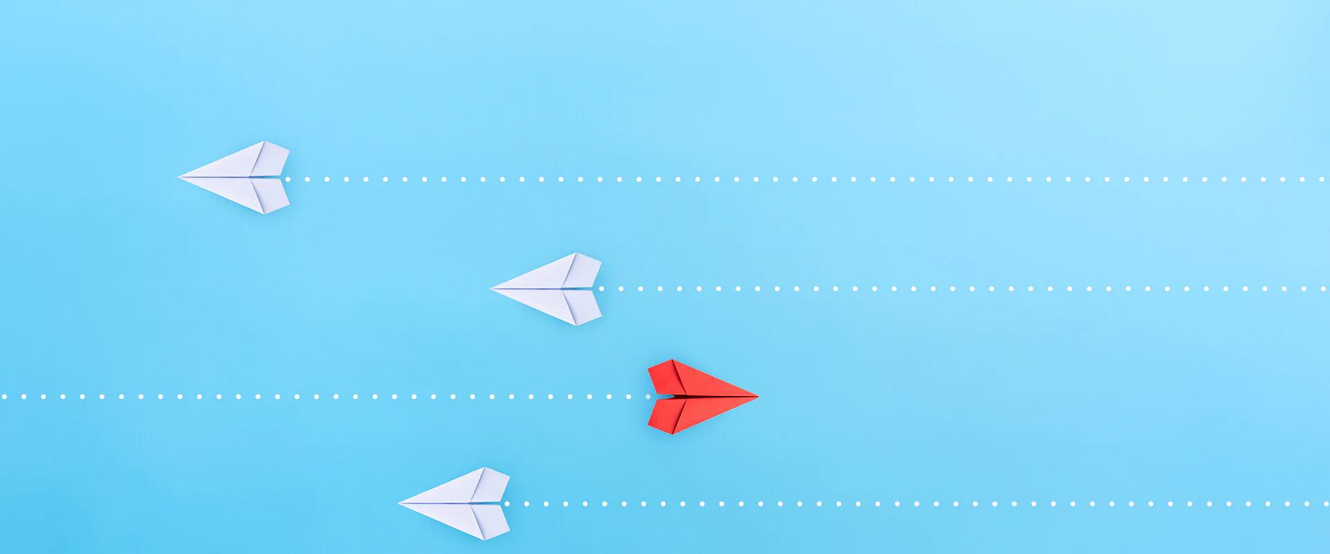 ThCM-Header-Innovationsfelder Bildbeschreibung / description: vier Papierflugzeuge von oben, die drei weißen fliegen nach links, der rote nach rechts